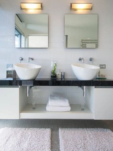 Modernes Bad mit Doppelwaschbecken und schwarzen Arbeitsplatten