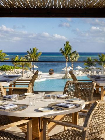 Terrasse mit Blick auf Pool und Meer mit gedeckten Tischen