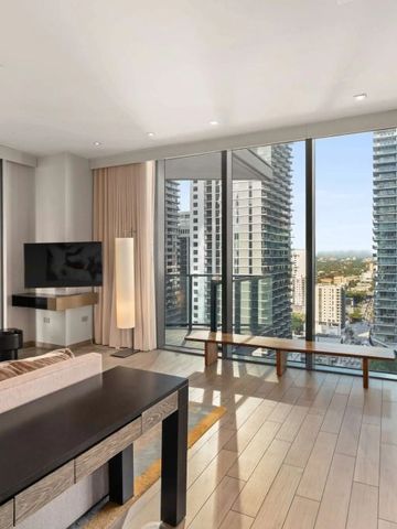 Heller Wohnbereich einer Suite mit Panoramafenstern und Stadtblick