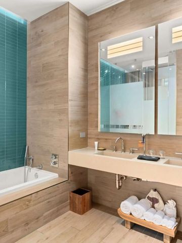 Modernes Badezimmer mit Holzelementen und grüner Fliesenwand