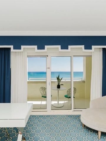 Helles Hotelzimmer mit Balkonblick auf das Meer und stilvoller Inneneinrichtung