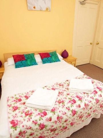 Doppelbett mit farbenfrohen Kissen und Blumenbettdecke