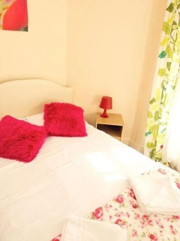 Helles Zimmer mit Doppelbett und blumigen Vorhängen