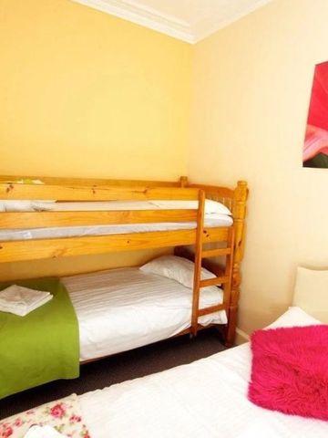 Schlafzimmer mit Etagenbett, Einzelbett und blumigem Kunstwerk an der Wand.