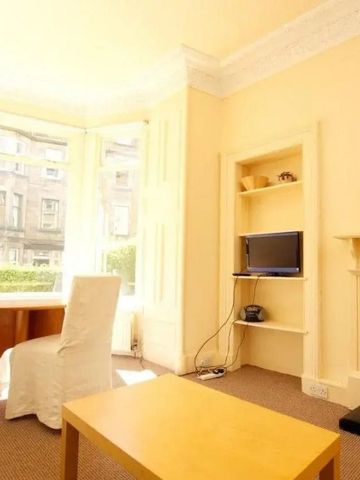 Heller Wohnbereich mit Esstisch, Stühlen und großem Fenster.