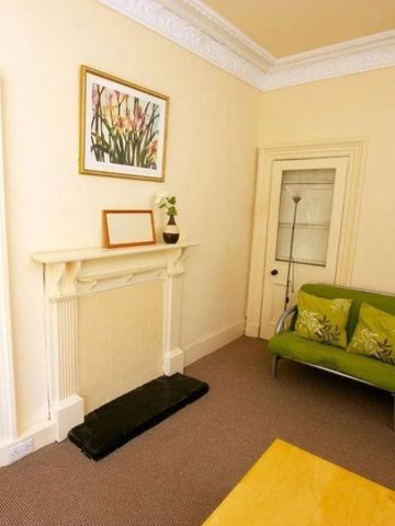 Wohnzimmer mit Kamin, kleinem Sofa und Kunst an der Wand.