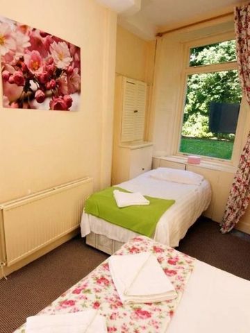 Gemütliches Zimmer mit zwei Einzelbetten und buntem Blumenschmuck.