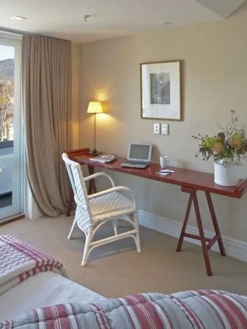 Helles Zimmer mit Schreibtisch, gemütlichem Sessel und Blick auf die Landschaft