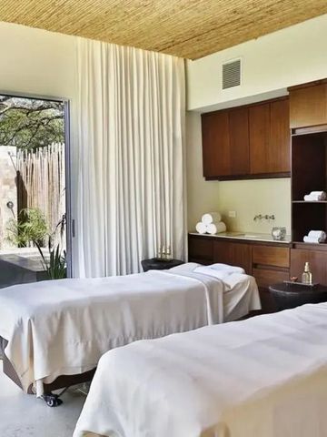 Spa-Behandlungsraum mit zwei Massagetischen und Gartenblick