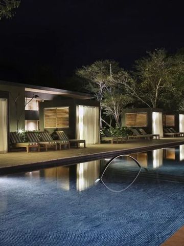 Beleuchteter Außenpool bei Nacht mit bequemen Liegen