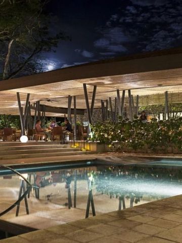 Restaurantbereich im Freien mit Pool und Beleuchtung bei Nacht