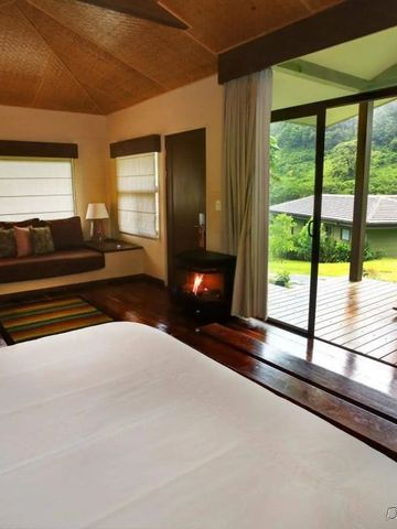 Elegantes Hotelzimmer mit Kamin und Terrasse mit Blick in tropischen Garten