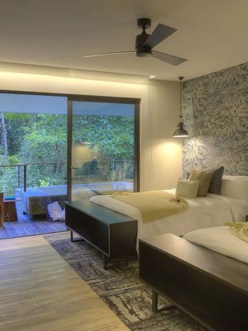 Modernes Zimmer mit Doppelbetten und Zugang zur Terrasse mit Waldpanorama