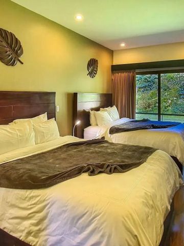 Doppelzimmer mit großen Betten und Blick auf die tropische Landschaft.