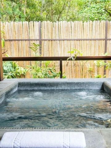 Privater Whirlpool auf einer Terrasse mit Bambuszaun und Pflanzen.