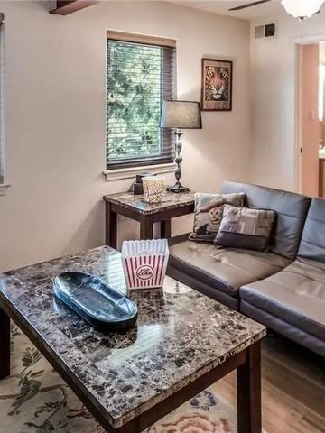 Wohnbereich mit Sofa und Couchtisch vor großen Fenstern und einem Gemälde