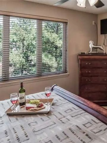 Blick aus dem Fenster auf Bäume von einem Schlafzimmer mit Tablett auf Bett