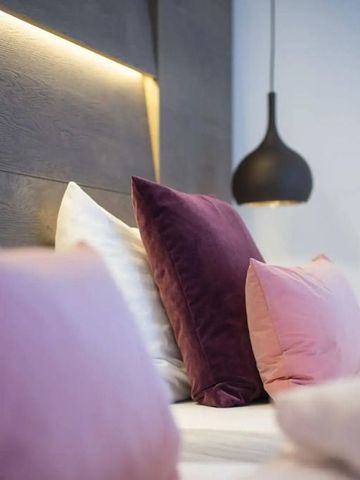 Luxuriöses Bett mit violetten Akzentkissen in modernem Zimmer