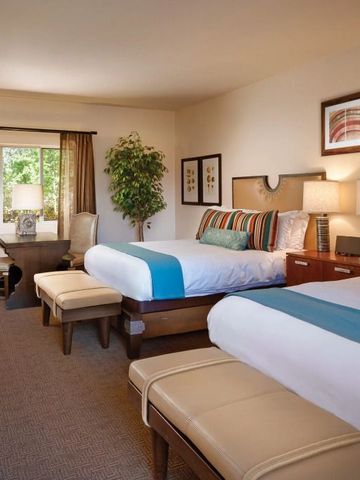 Geräumiges Hotelzimmer mit zwei Betten, Sitzbereich und großem Fenster