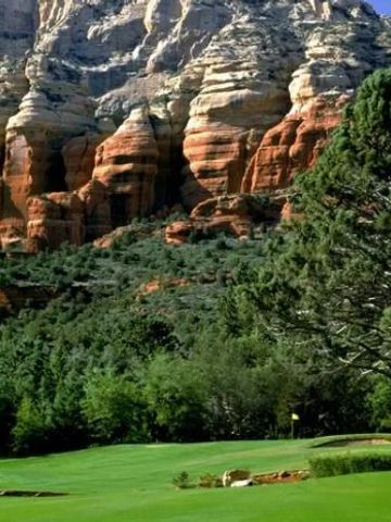 Grüner Golfplatz umgeben von beeindruckenden roten Felsen und Bäumen