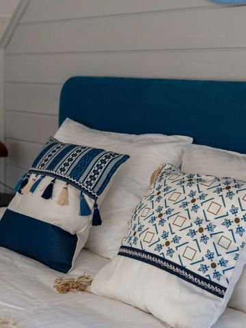 Gemütliches Bett mit blauen und weißen Zierkissen