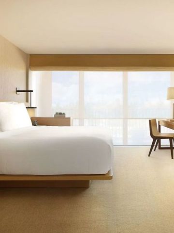 Geräumiges Hotelzimmer mit großem Bett und Schreibtisch, viel Tageslicht.