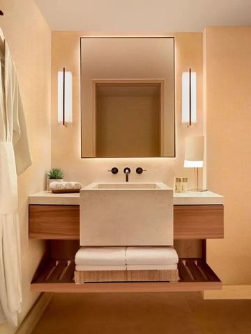 Waschbereich im Badezimmer mit großem Spiegel und dezenter Beleuchtung.