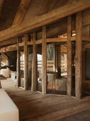 Rustikales Wohnzimmer mit großen Fenstern und Holzbalken