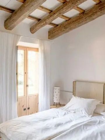Schlafzimmer mit Holzbalkendecke und weißem Interieur im Hotel Es Racó d'Artà