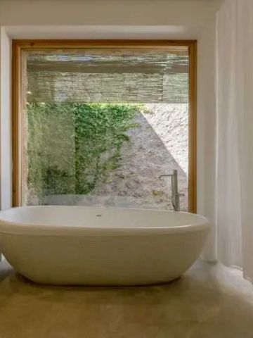 Freistehende Badewanne mit Ausblick auf privaten Gartenbereich