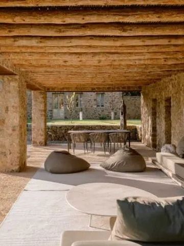 Gemütliche Terrasse mit rustikalen Holzbalken und Lounge-Möbeln im Freien.