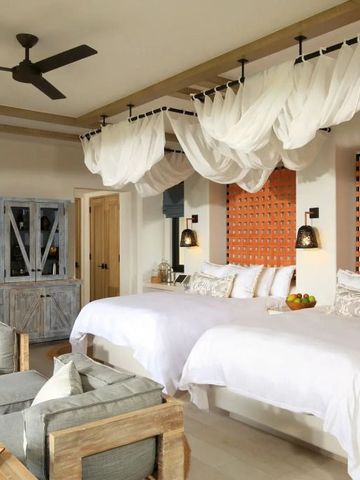 Großzügiges Zimmer mit Himmelbett und modernen Details in warmen Tönen.