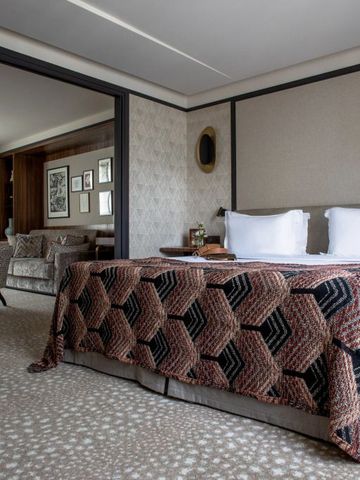 Großzügiges Hotelzimmer mit edler Bettwäsche und einladendem Sitzbereich.