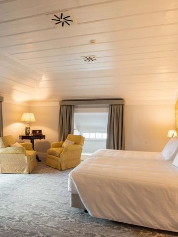 Gemütliches modernes Schlafzimmer mit Sitzbereich und warmen Farben.