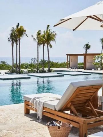 Infinity-Pool mit Liegestühlen und Sonnenschirmen mit Blick auf das Meer.