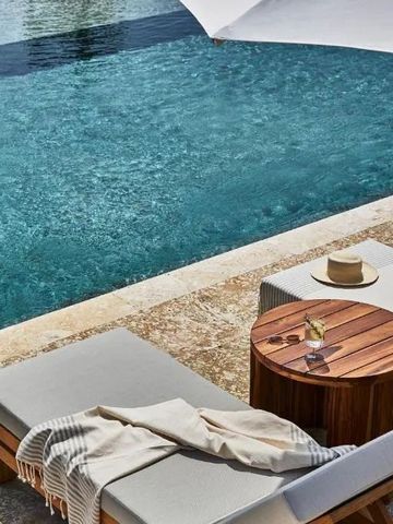 Sonnenliegen und Tisch an einem strahlend blauen Pool