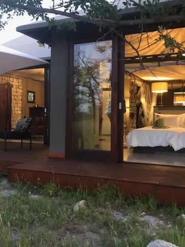 Offenes Zimmer mit Doppelbett und großer Glasfront zur Terrasse