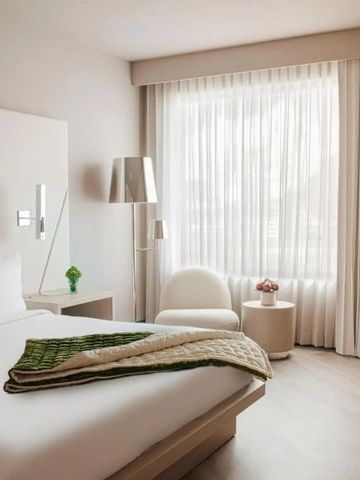 Modern eingerichtetes Hotelzimmer mit großem Fenster und gemütlichem Bett