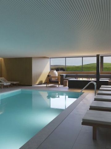 Innenansicht eines eleganten Innenpools mit Liegestühlen und Panoramablick