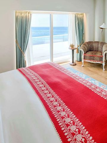 Zimmer mit Blick auf den Ozean, breites Bett und roter Akzentdecke