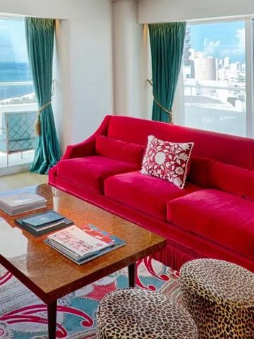 Luxuriöse Suite mit rotem Sofa, Panoramafenstern und Stadtblick