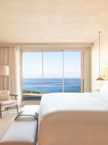 Luxuriöses Zimmer mit Meerblick und großen Fenstern zur Küste.