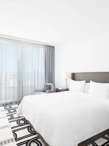 Helles Hotelzimmer mit großem Bett und Blick auf das Meer durch große Fenster