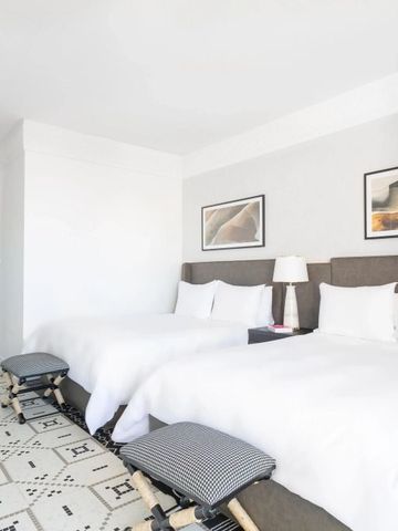 Zwei Doppelbetten in einem geräumigen Hotelzimmer mit heller Einrichtung