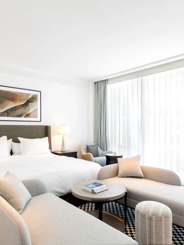 Helles Hotelzimmer mit großer Fensterfront und eleganter Sitzecke