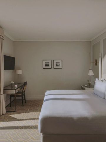 Helles Gästezimmer mit Doppelbett und Blick auf den See im Fairmont Le Montreux Palace