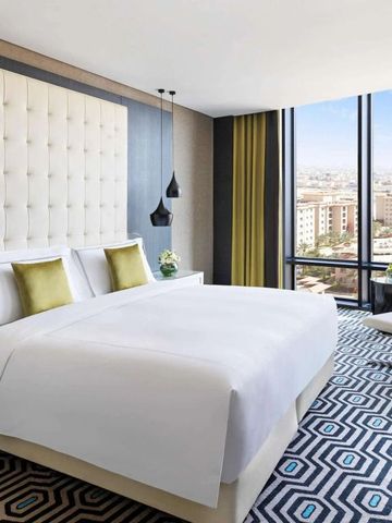 Geräumiges Hotelzimmer mit großem Bett und Panoramafenster mit Stadtblick