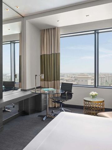 Zimmer mit Schreibtisch, Fernseher und großen Fenstern mit Aussicht