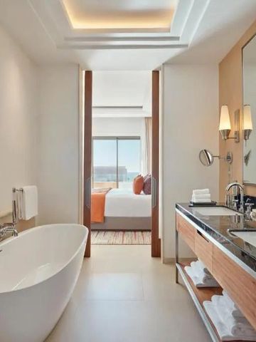 Luxuriöses Badezimmer mit freistehender Badewanne und Blick ins Schlafzimmer