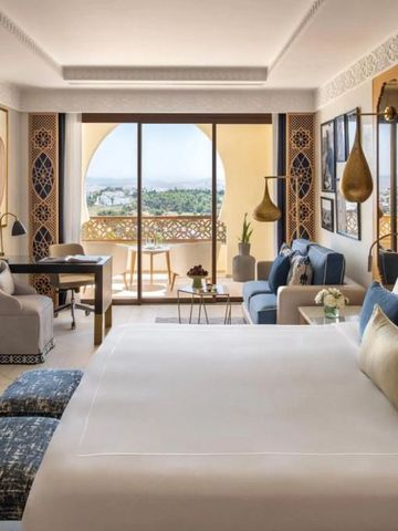 Großes Zimmer mit Bett und Sitzbereich mit Panoramablick vom Balkon